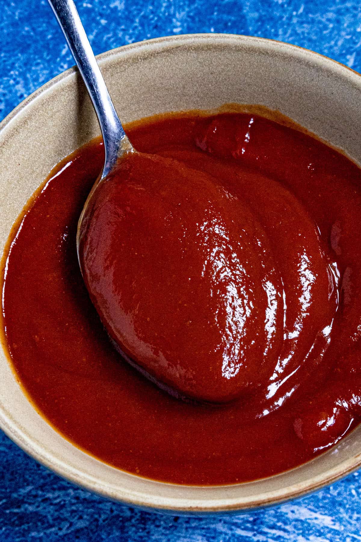 A small bowl filled with tomatoey meatloaf glaze, with a spoon