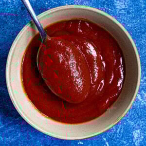 A bowl filled with thick meatloaf glaze, with a spoon