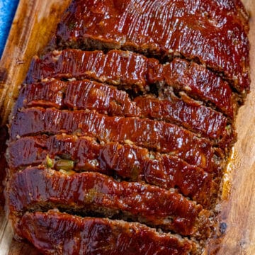 A sliced meatloaf on a cutting board, slathered with extra meatloaf glaze