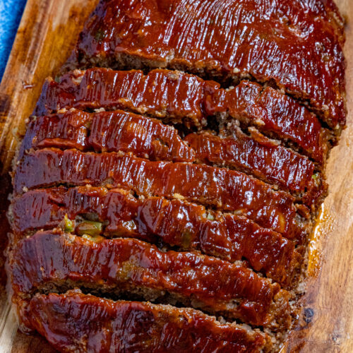 A sliced meatloaf on a cutting board, slathered with extra meatloaf glaze