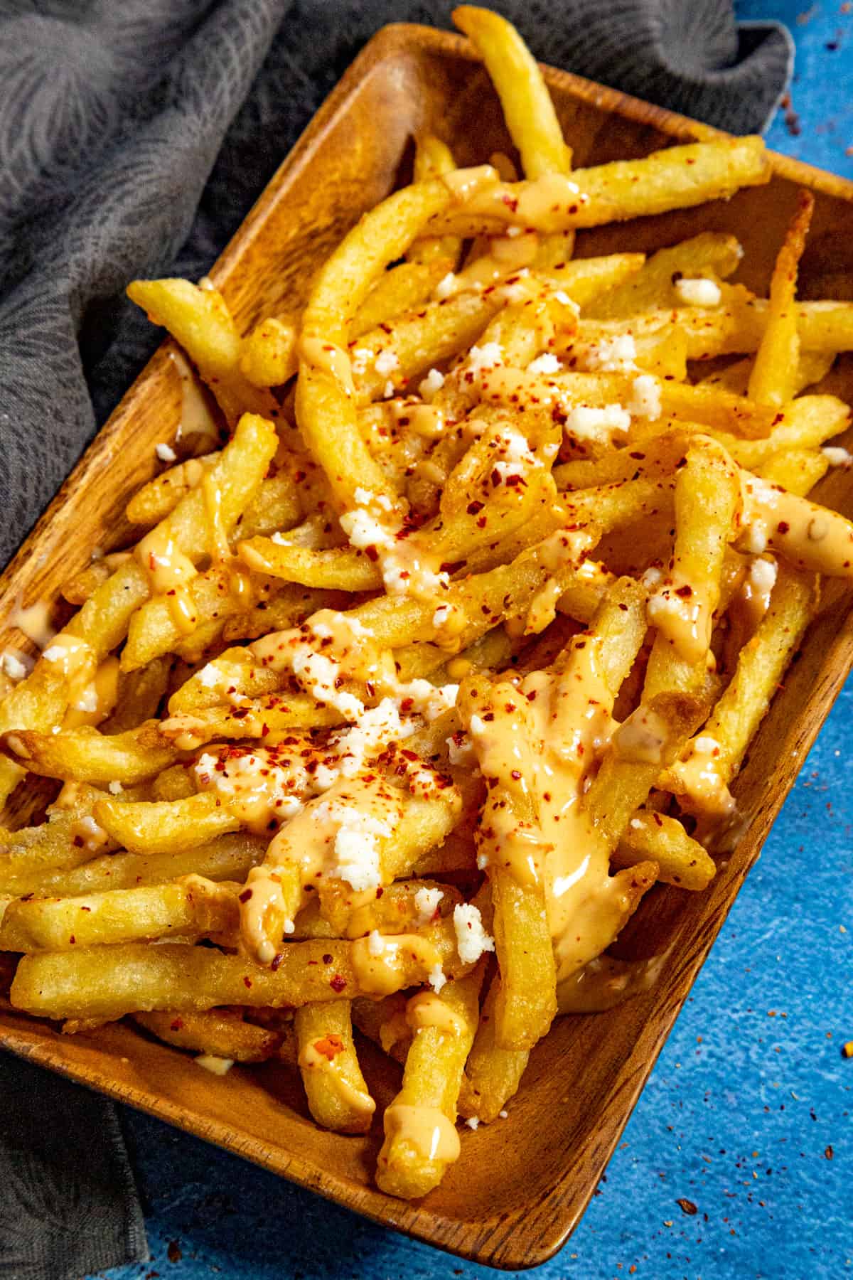 A basket of crispy French fries drizzled with creamy, spicy Belgian samurai sauce