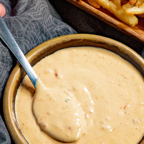 A bowl filled with creamy samurai sauce, with french fries on the side