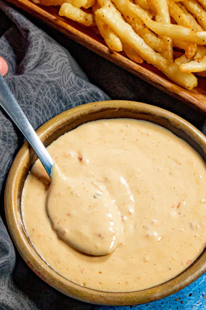 A bowl filled with creamy samurai sauce, with french fries on the side