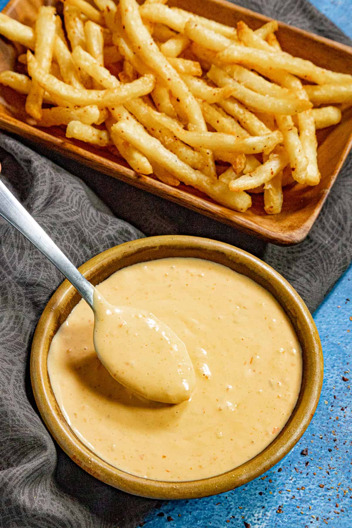 Taking a scoop of Samurai Sauce Recipe (Belgian Spicy Mayo/Fry Sauce) from the bowl with a spoon