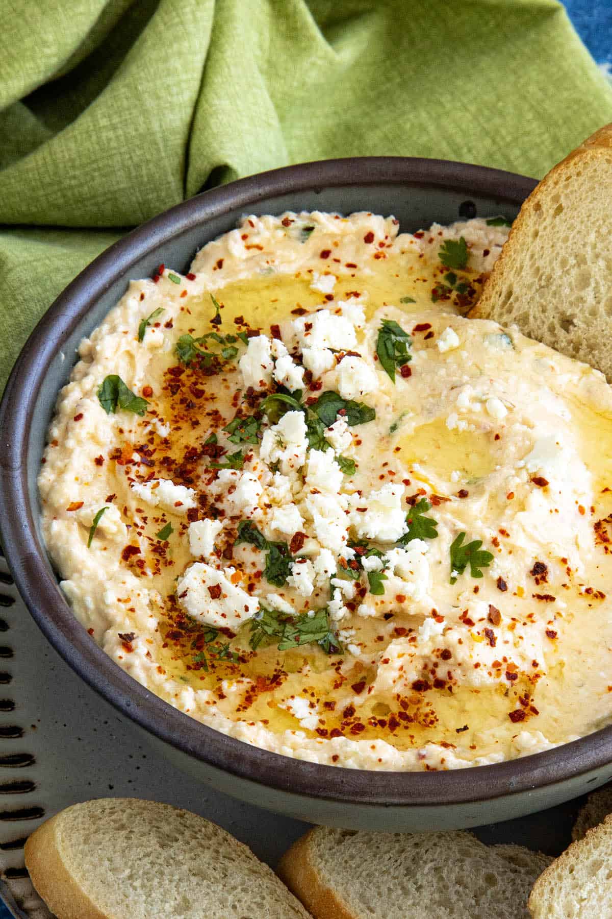 Greek Spicy Feta Dip (Tirokafteri) in a bowl, topped with fresh chopped parsley, red chili flakes, and crumbly feta cheese