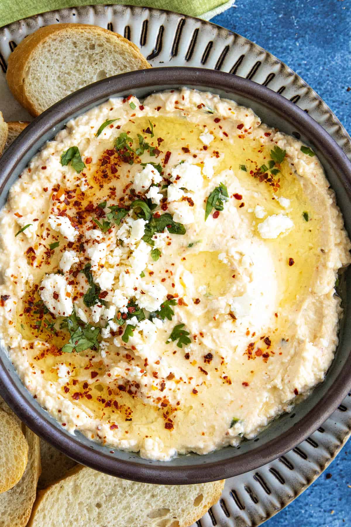 A bowl of Greek Spicy Feta Dip (Tirokafteri) topped with olive oil and fresh chopped parsley