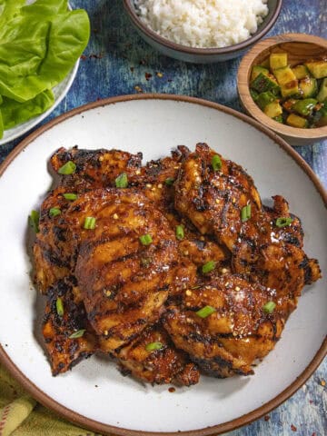 Dak Bulgogi (Korean BBQ Chicken) served on a plate with a bowl of rice and kimchi on the side