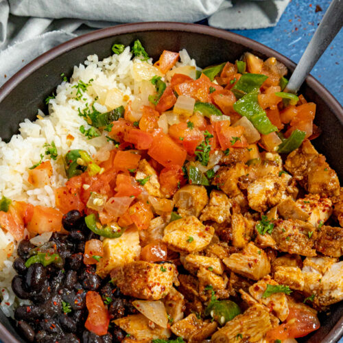 A bowl of chopped chipotle chicken served with white rice and black beans, topped with chunky salsa