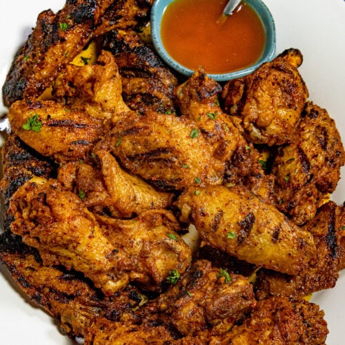 Cowboy butter chicken wings piled up on a serving dish, served with a bowl of cowboy butter on the side