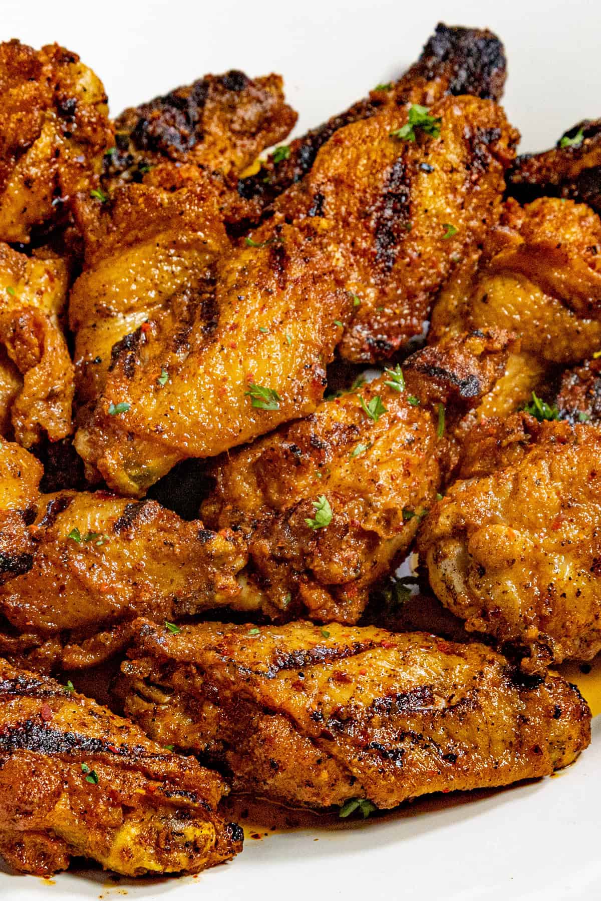 Crispy chicken wings on a serving platter, garnished with fresh chopped parsley