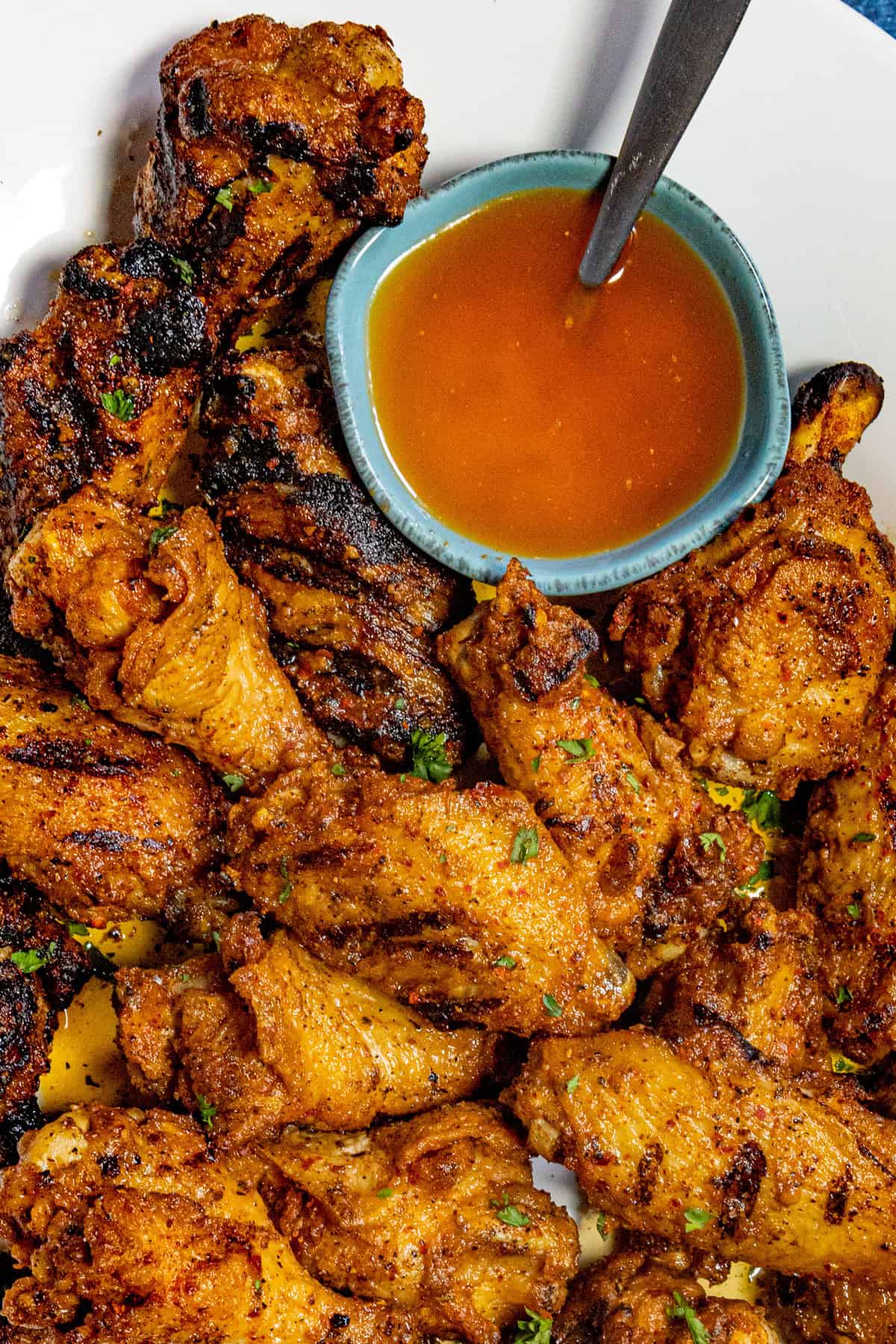 A bowl of cowboy butter nestled into a platter loaded with chicken wings