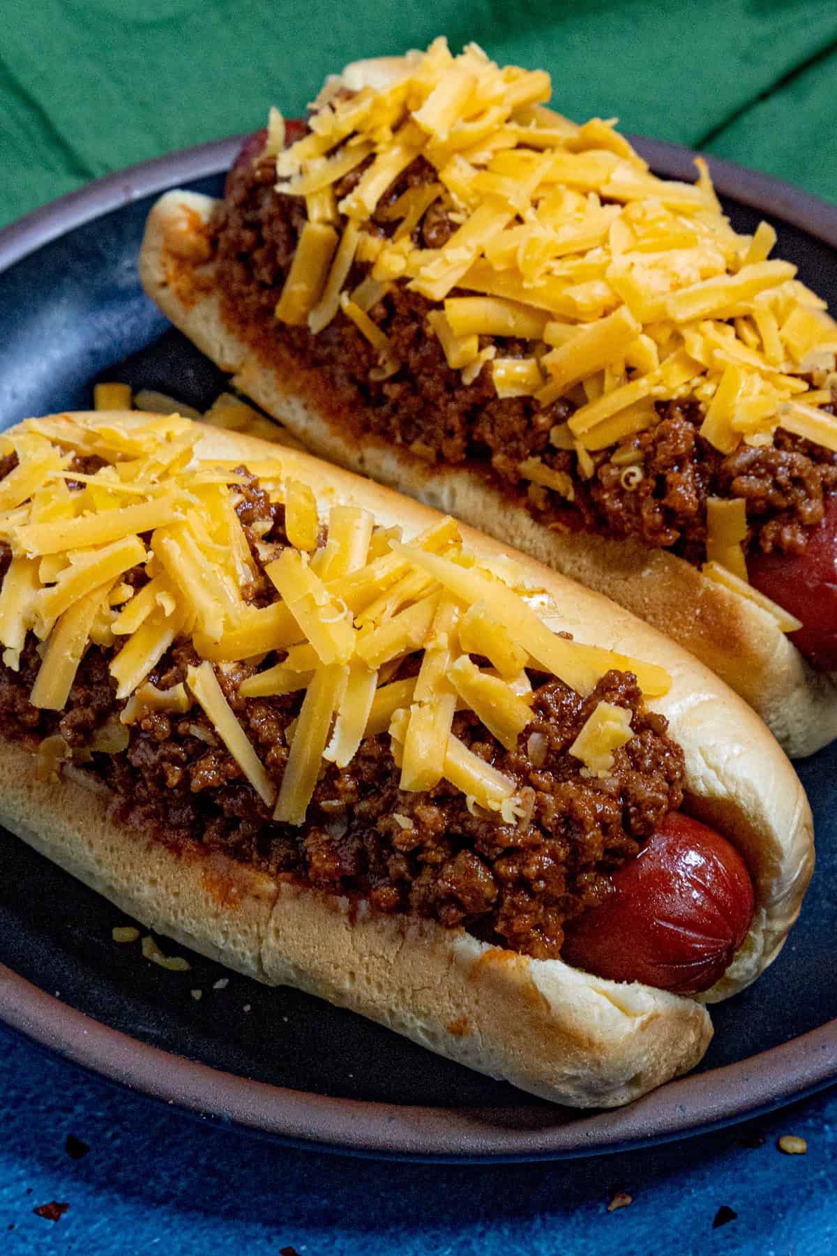 Two chili dogs topped with thick, meaty hot dog chili and shredded cheddar cheese