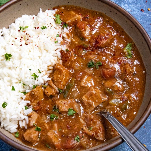 A hearty bowl of chicken Sauce Piquante served over white rice, with a spoon