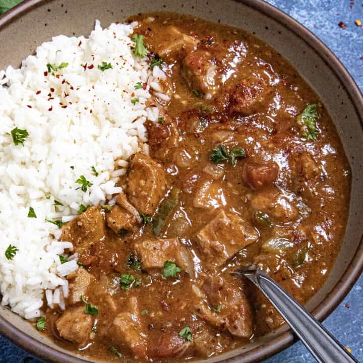 A hearty bowl of chicken Sauce Piquante served over white rice, with a spoon
