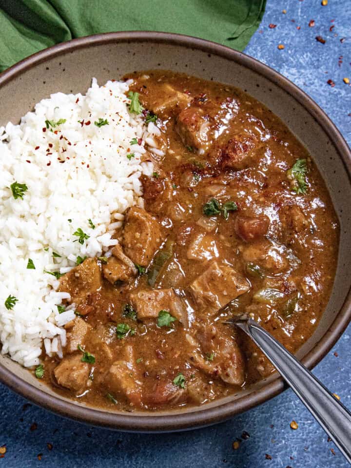 A hearty bowl of chicken Sauce Piquante served over white rice, with a spoon