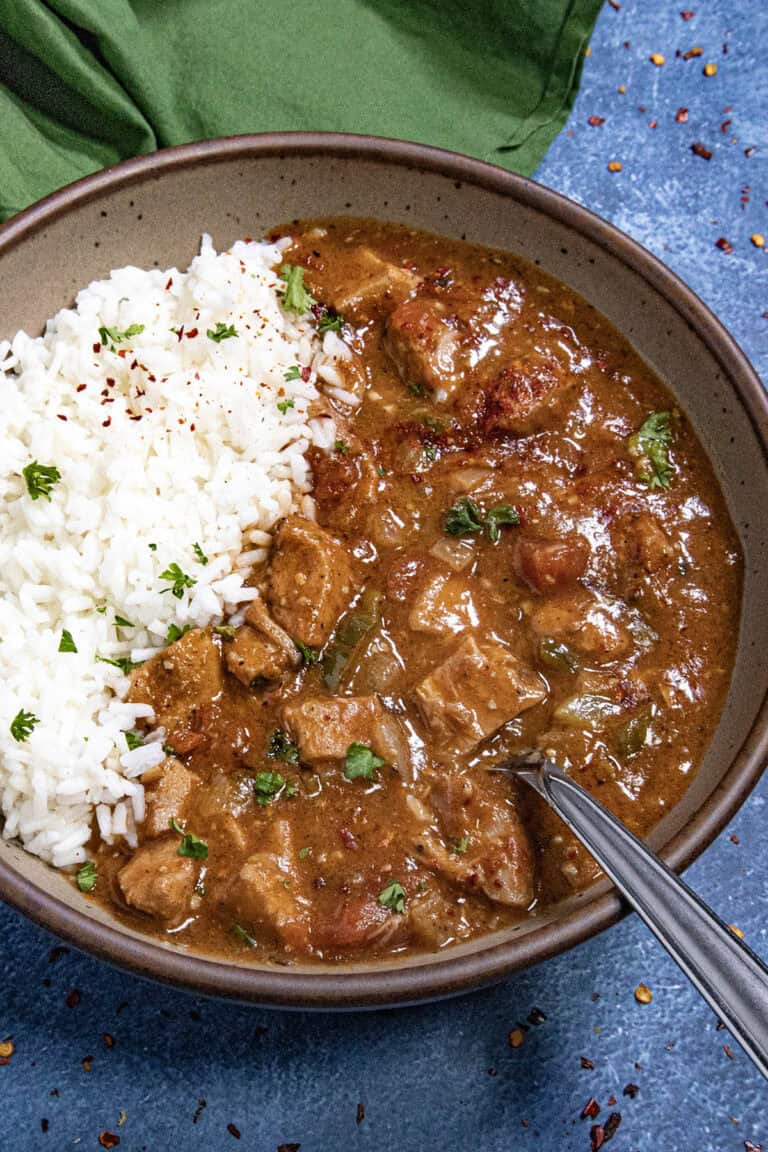A hearty bowl of chicken Sauce Piquante served over white rice, with a spoon
