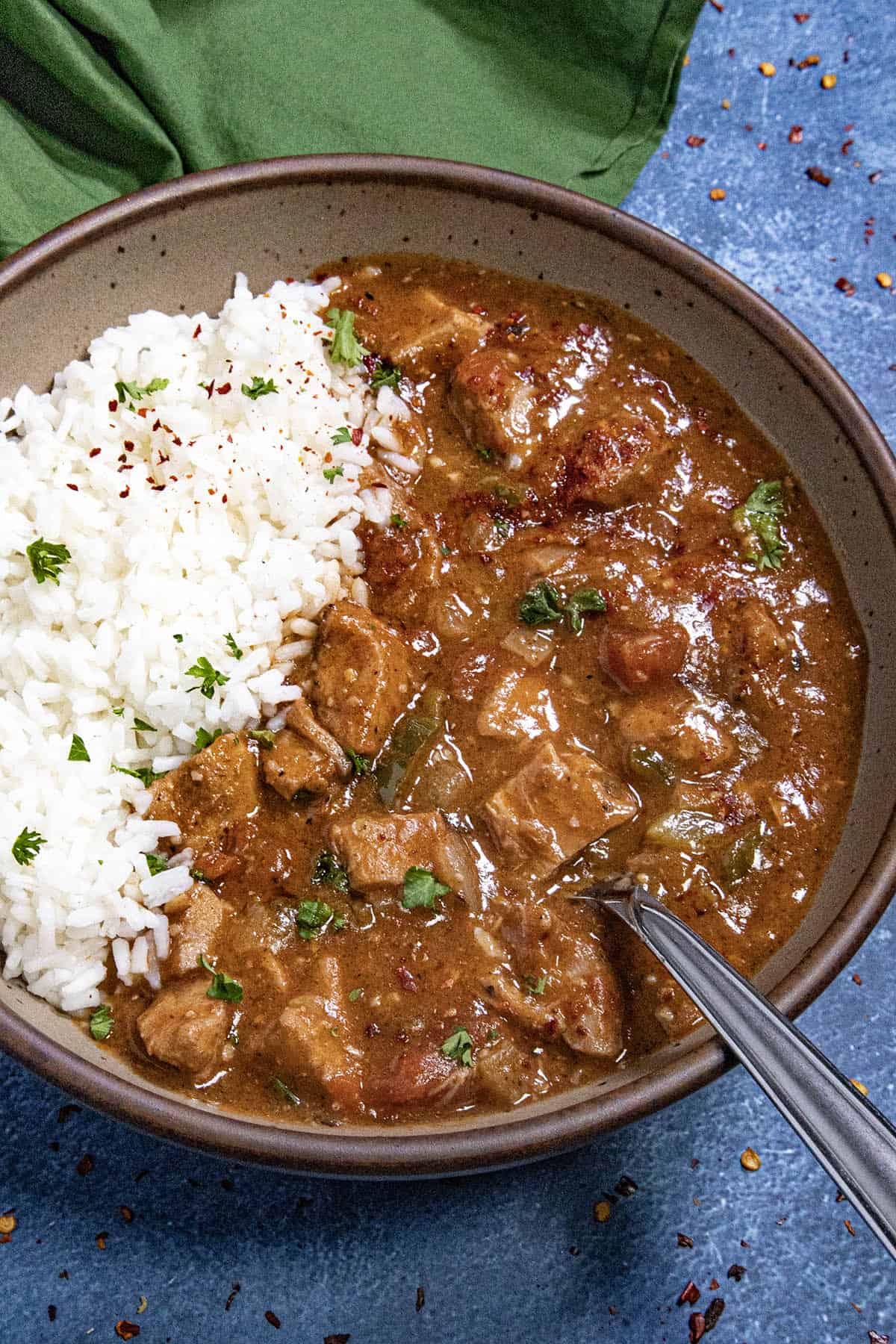 A hearty bowl of chicken Sauce Piquante served over white rice, with a spoon
