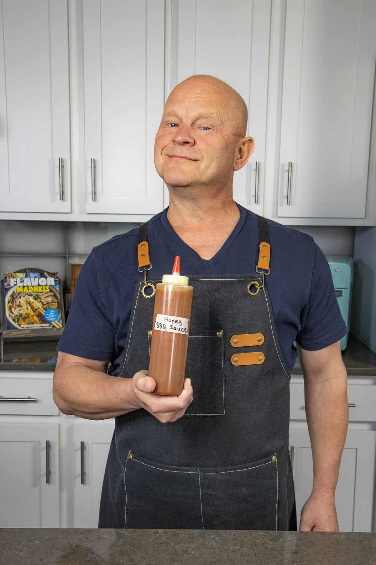 Mike from Chili Pepper Madness holding a bottle of freshly made Spicy Honey BBQ Sauce