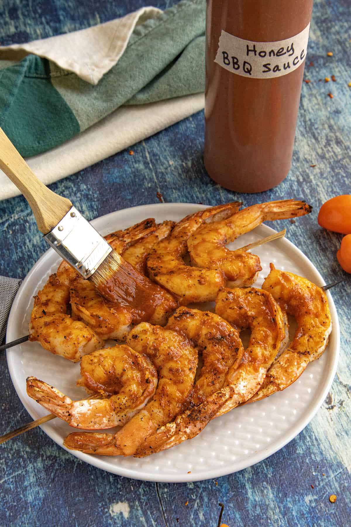 Grilled shrimp skewers being brushed with habanero-honey bbq sauce