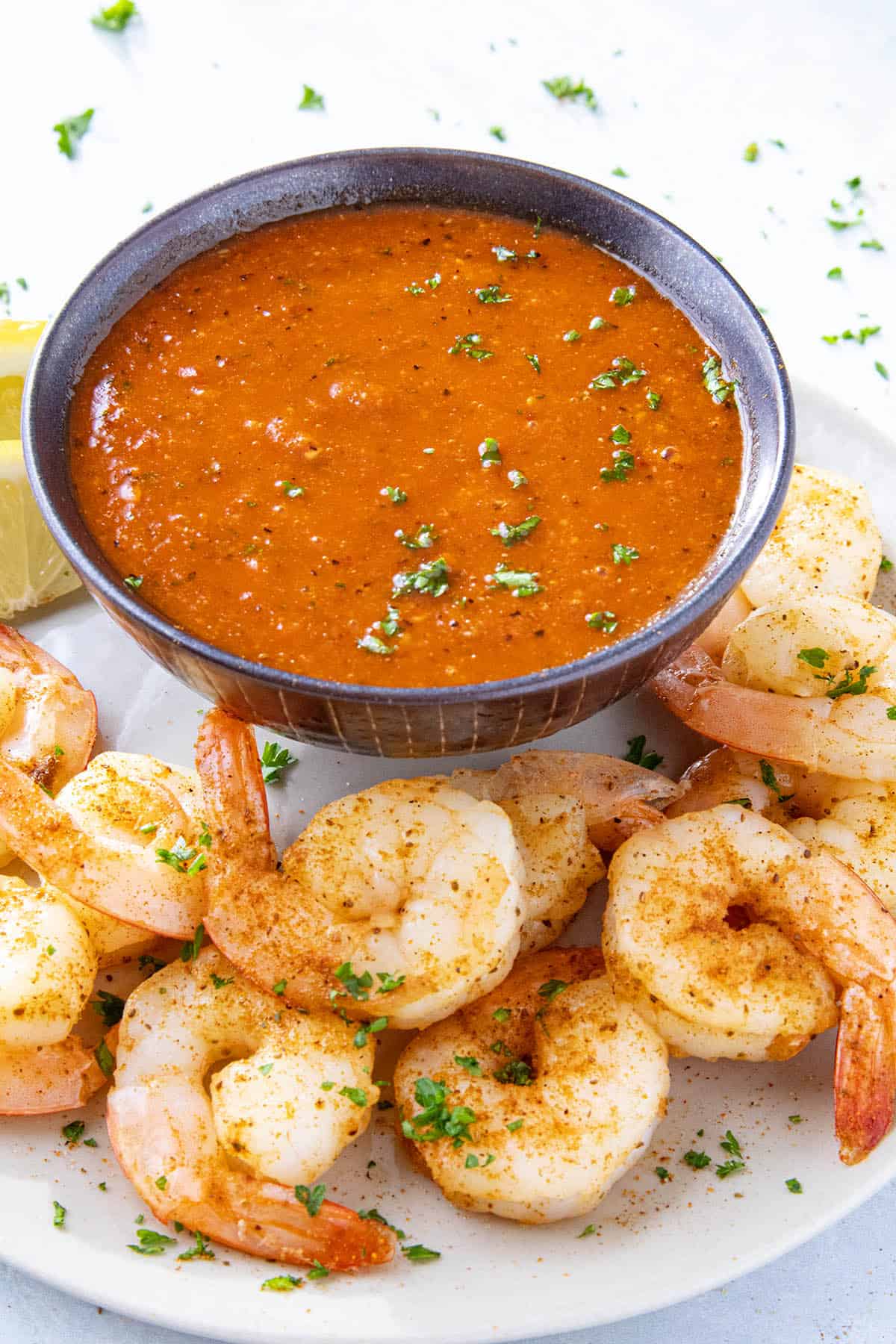 Homemade cocktail sauce in a serving bowl, placed on a platter of spicy blackened shrimp