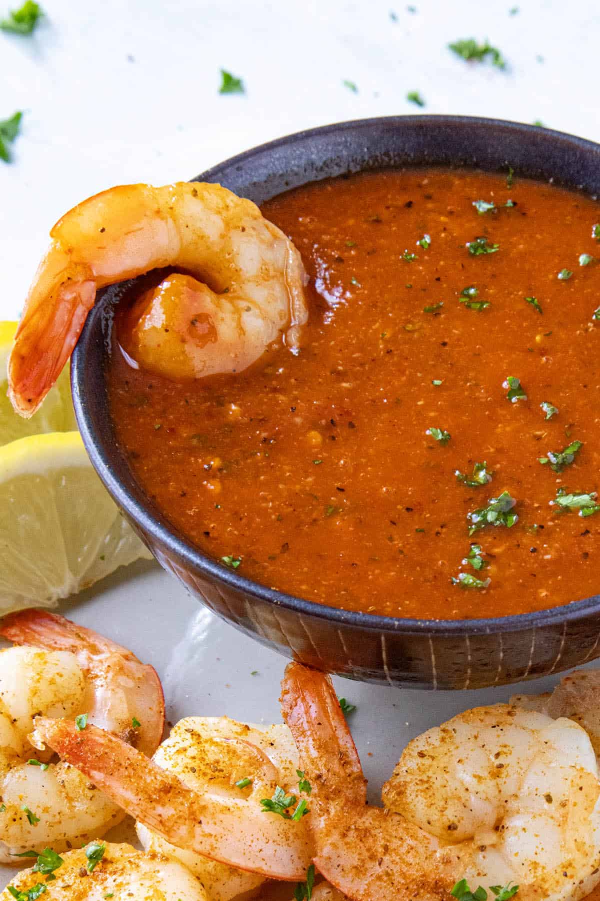 A piece of juicy shrimp dunked into a bowl of homemade cocktail sauce