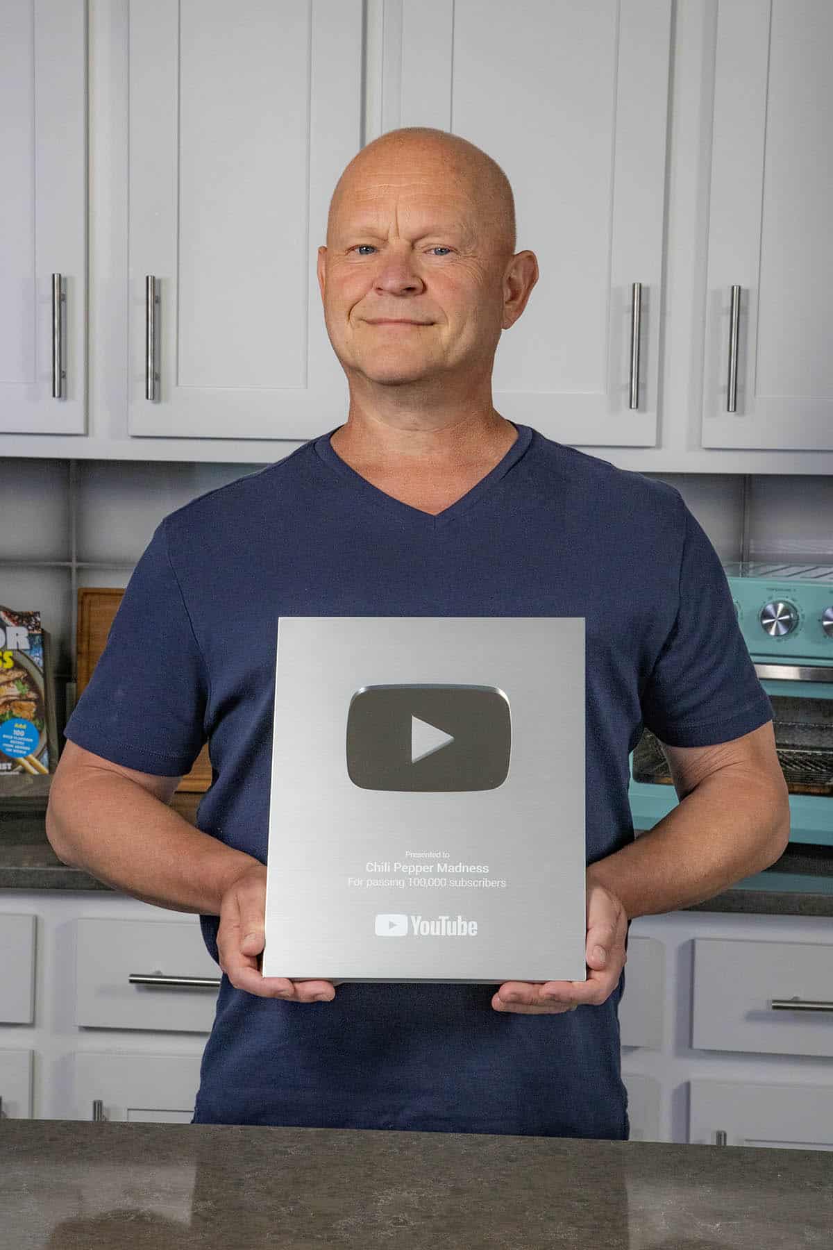 Mike Hultquist of Chili Pepper Madness holding his 100,000 Youtube Subscribers plaque, after having achieved Youtube Creator of the Day.