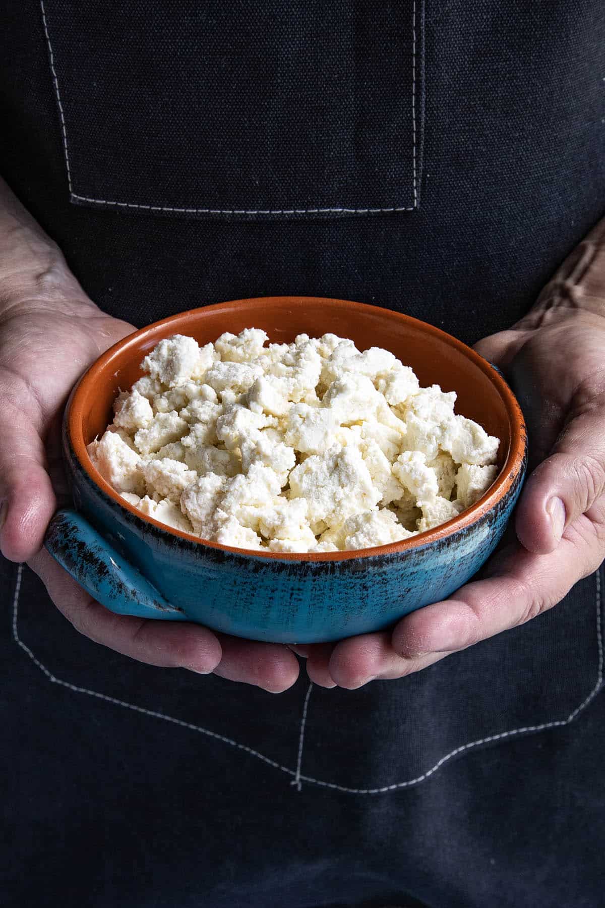 Mike from ChiliPepperMadness.com holds a blue and brown bowl filled with crumbled Fresh Queso Fresco.