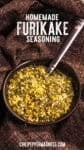 A bowl of homemade Japanese Furikake Seasoning with a spoon sits on a dark textured cloth, featuring text reading Homemade Furikake Seasoning
