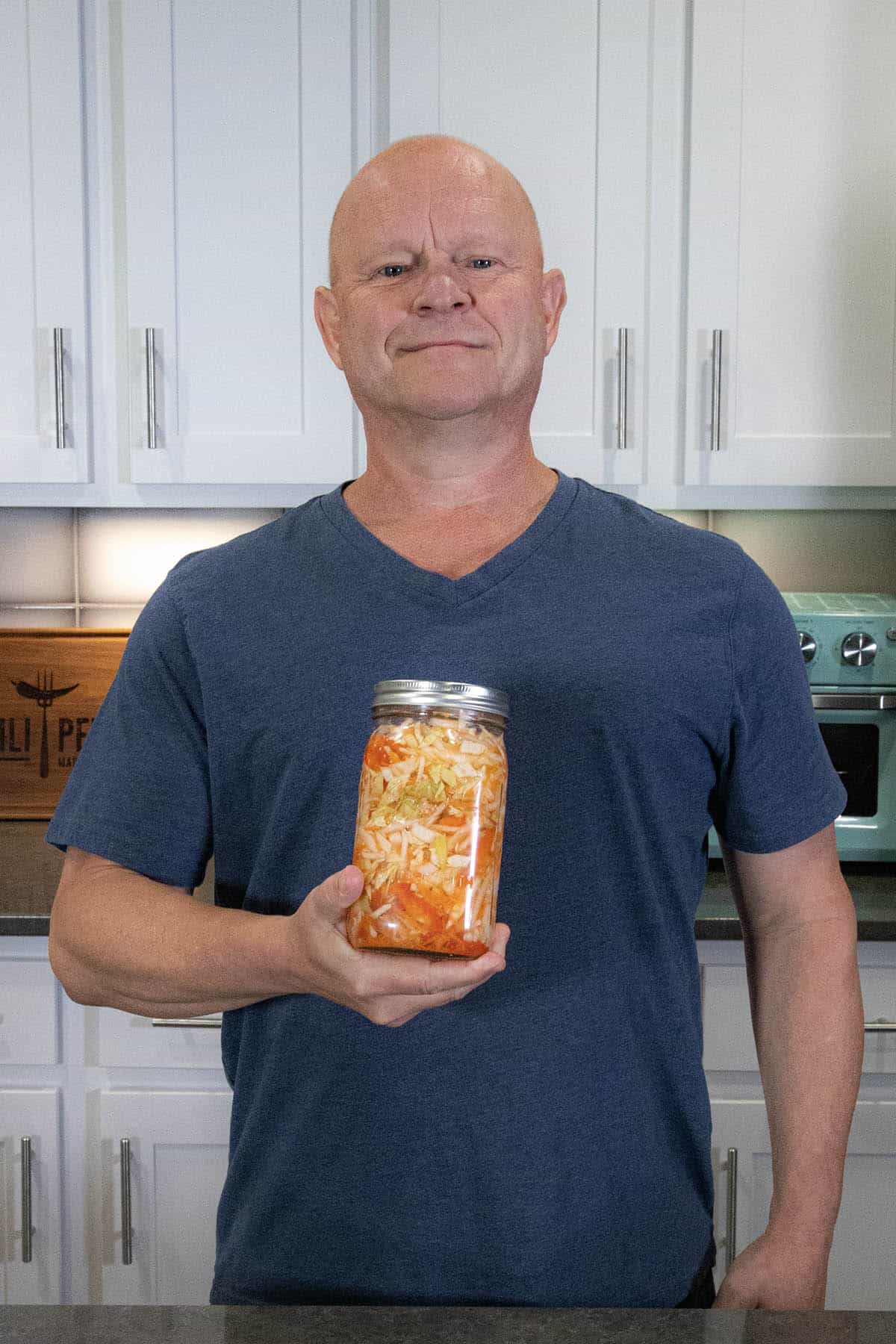 Mike from Chili Pepper Madness holding a jar of freshly made Pikliz (Spicy Haitian Pickled Slaw)