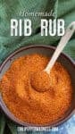 A bowl filled with a rich, reddish-brown rib rub spice blend, with a metal spoon resting inside. The image features text reading Homemade Rib Rub and the website chilipeppermadness.com at the bottom.