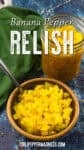 A bowl and jar filled with bright yellow Banana Pepper Relish, with a spoon in the bowl, set on a blue surface next to a green cloth. Text reads Banana Pepper Relish chilipeppermadness.com.