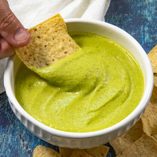 Mike scooping creamy guacachile from a bowl with a tortilla chip