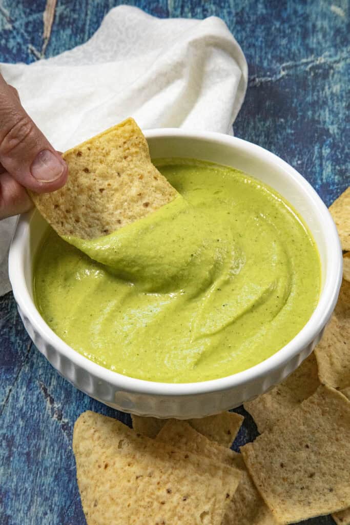 Mike scooping creamy guacachile from a bowl with a tortilla chip