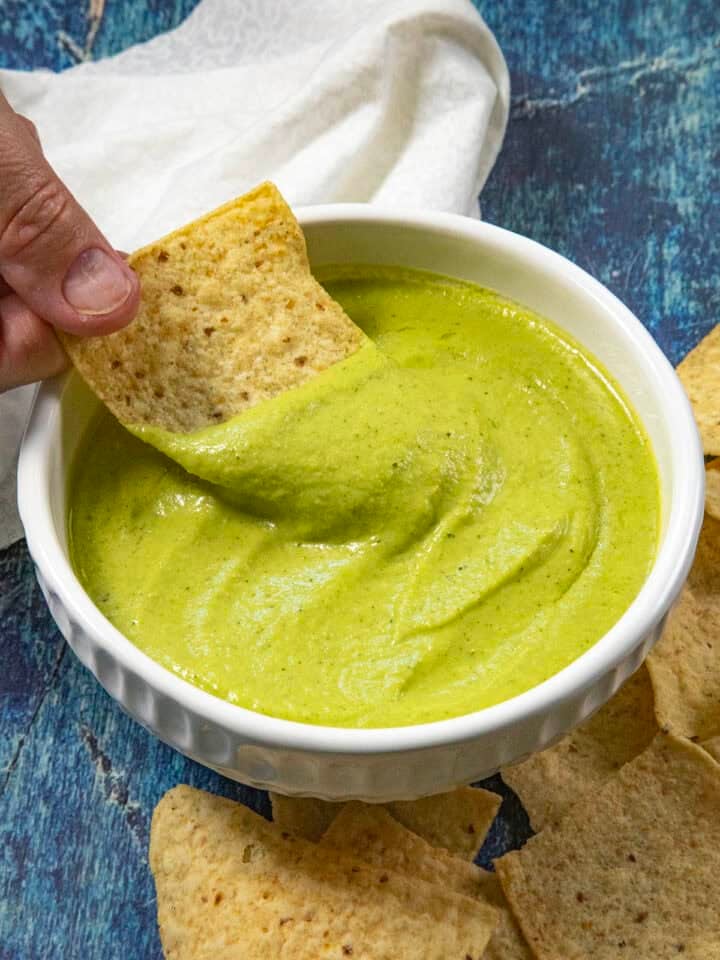 Mike scooping creamy guacachile from a bowl with a tortilla chip