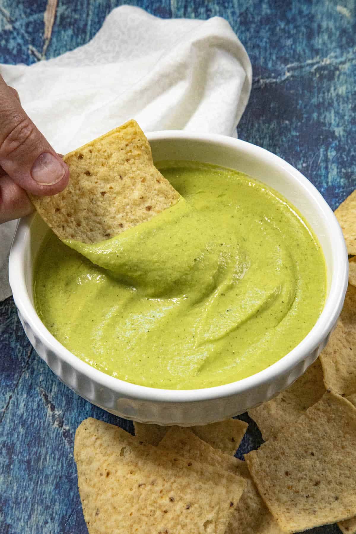Mike scooping creamy guacachile from a bowl with a tortilla chip