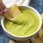 Mike scooping creamy guacachile from a bowl with a tortilla chip