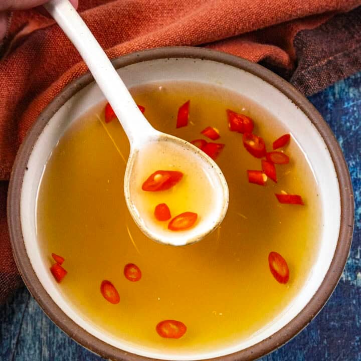 Mike from Chili Pepper Madness scooping golden Nuoc Cham (Vietnamese Dipping Sauce) from a bowl with a white spoon