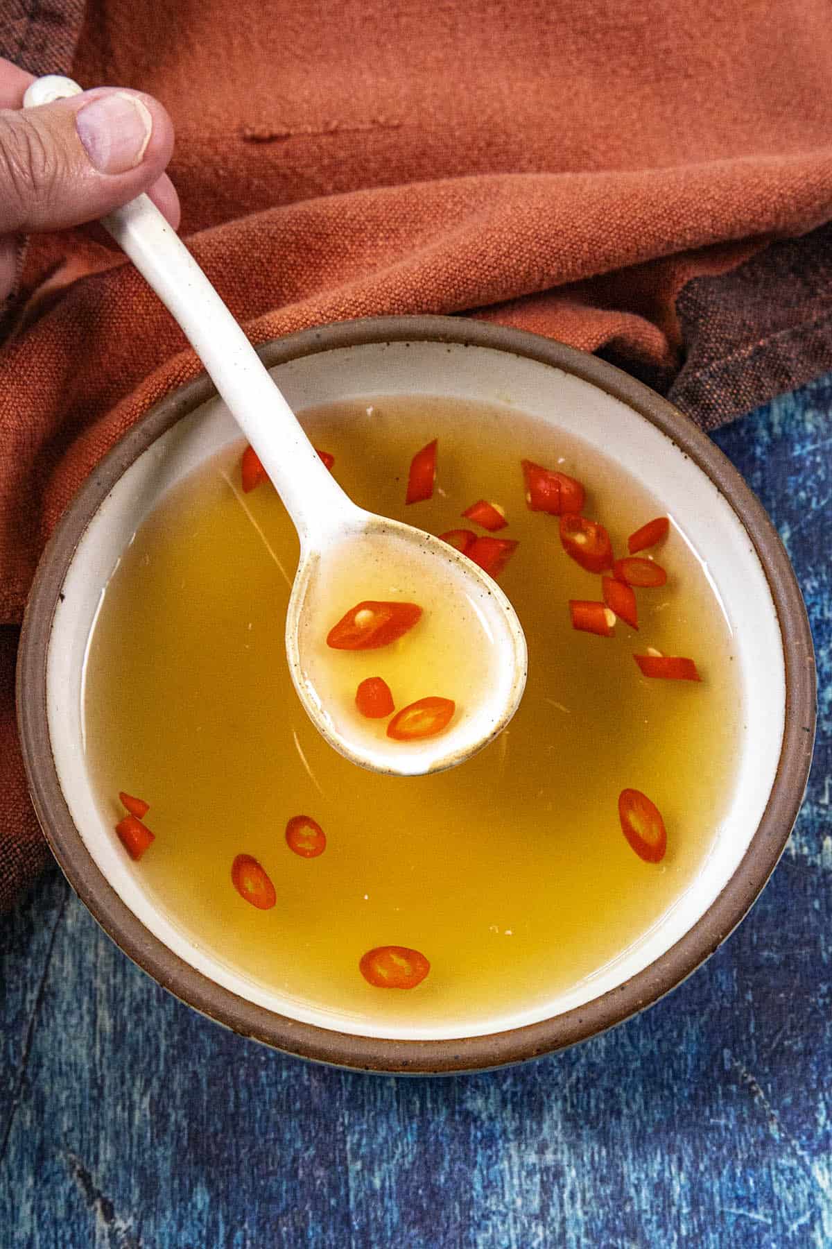 Mike from Chili Pepper Madness scooping golden Nuoc Cham (Vietnamese Dipping Sauce) from a bowl with a white spoon
