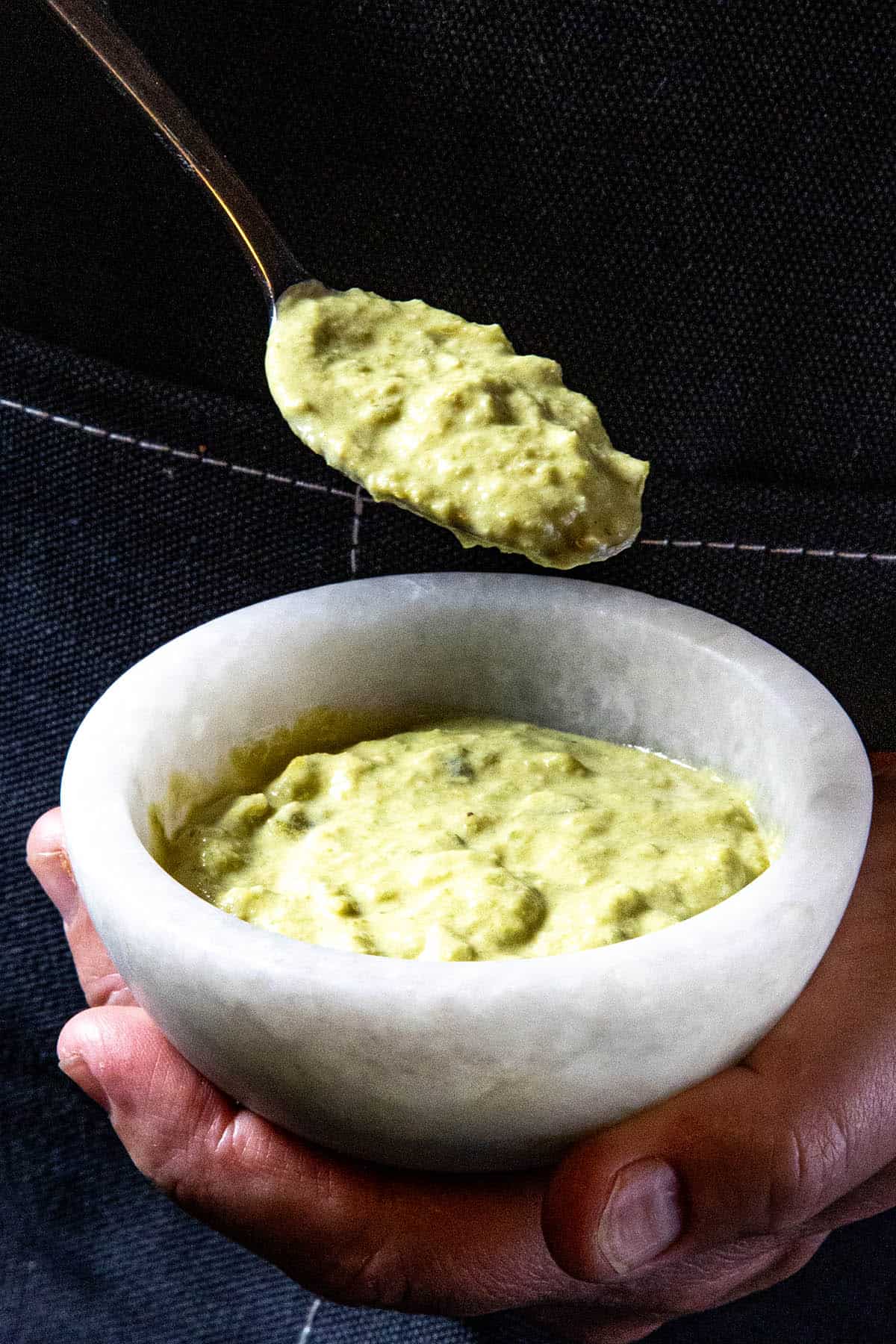 Mike holding a bowl of thick roasted jalapeno sauce, lifting some with a spoon