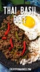 A black plate with Thai Basil Beef (Pad Kra Pao Neua), red chilies, green vegetables, white rice, and a sunny-side-up egg. The text reads Thai Basil Beef and chilipeppermadness.com.