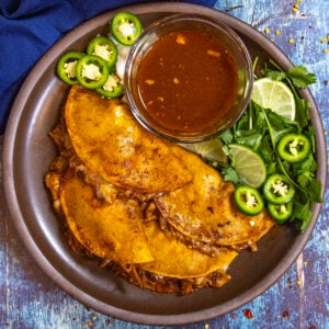 Four Chicken Birria Tacos (Birria de Pollo) on a plate, served with birria consome dipping sauce