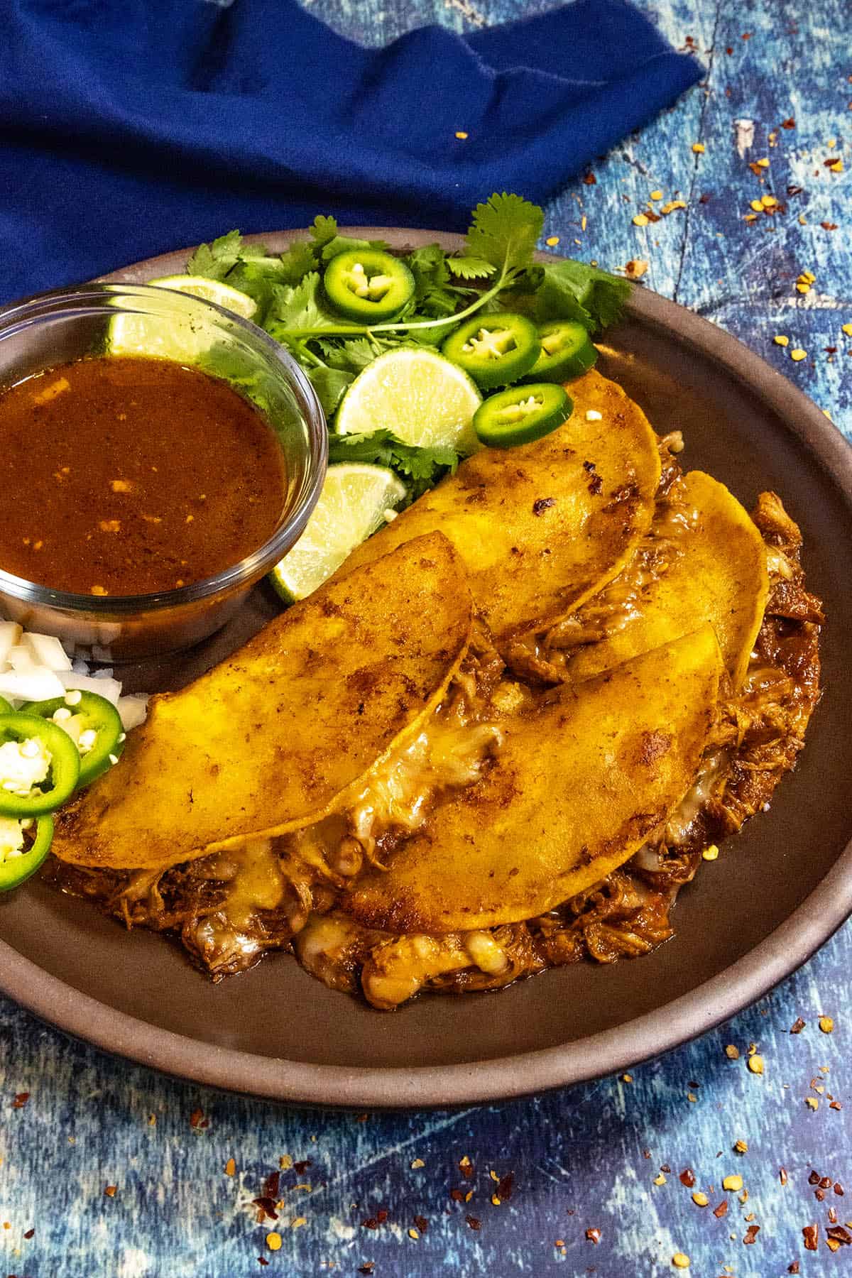 Four Chicken Birria Tacos (Birria de Pollo) served with fresh lime, jalapeno slices, cilantro, and consome