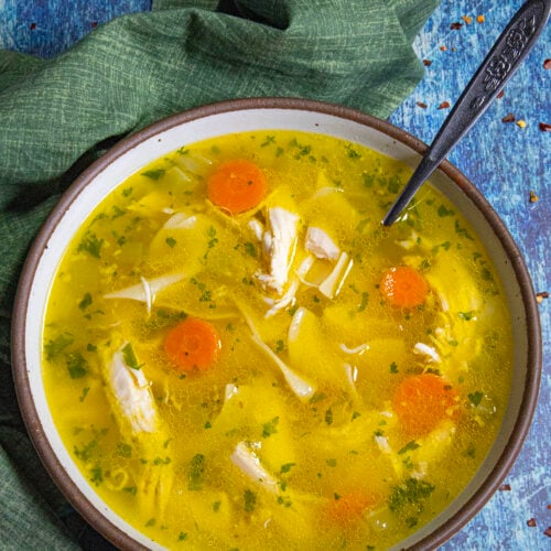 A large bowl filled with golden Homemade Chicken Noodle Soup, served with a spoon