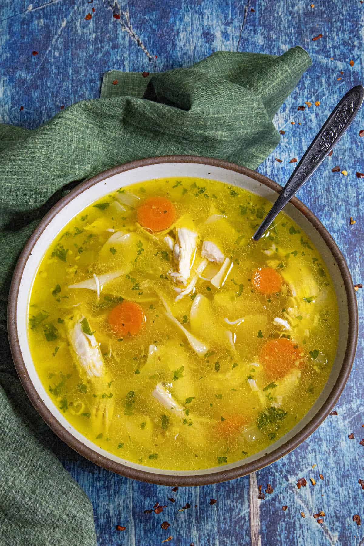 A large bowl filled with golden Homemade Chicken Noodle Soup, served with a spoon