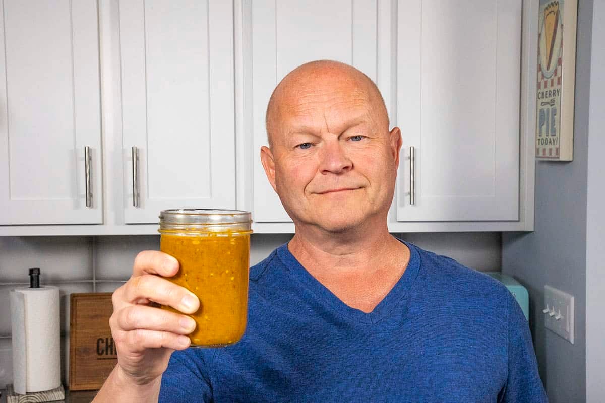 Mike Hultquist holding a jar of homemade peri peri sauce.