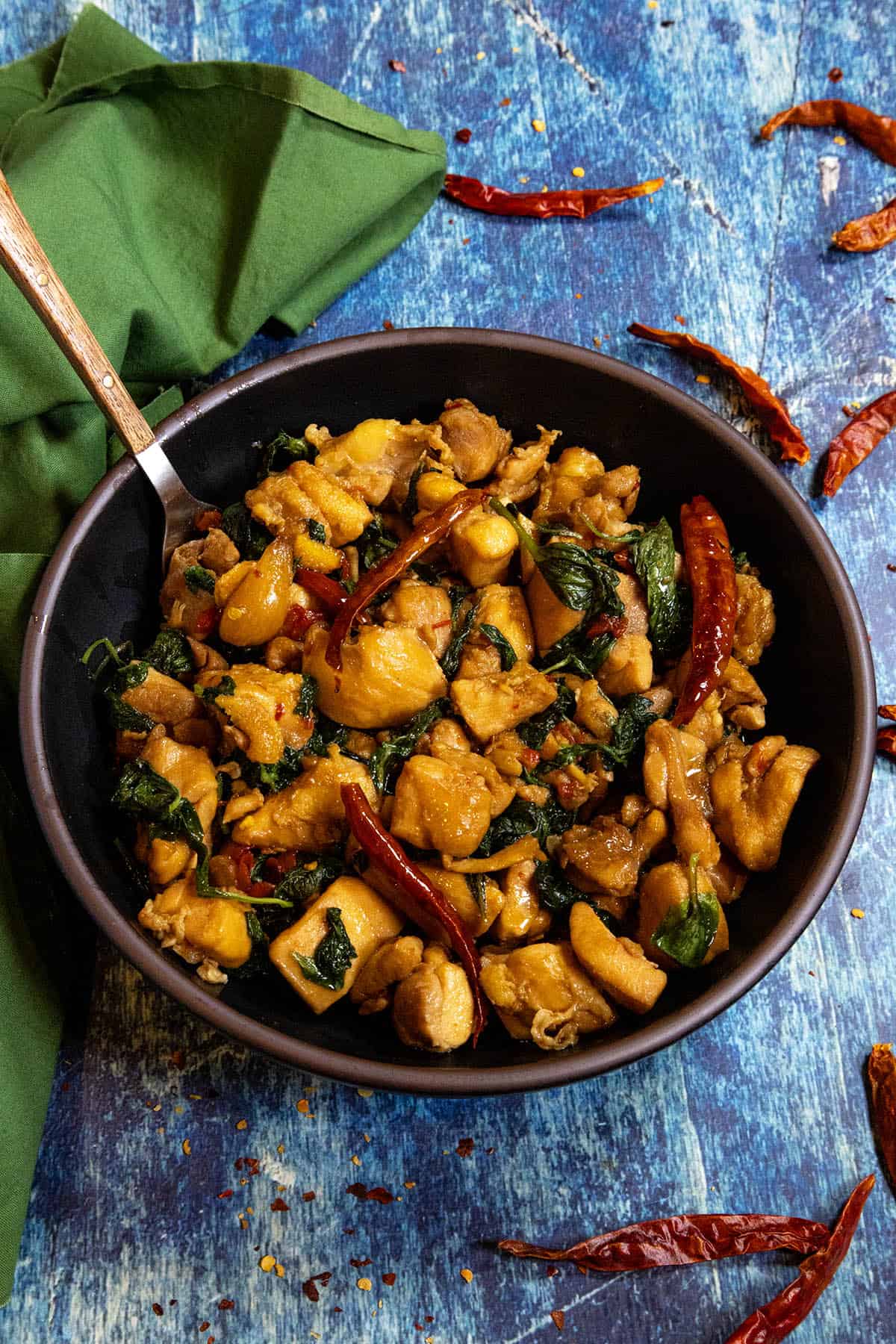 A bowl filled with saucy Three Cup Chicken (San Bei Ji), with lots of basil and hot chilies